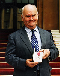 Rob Freeman displaying his OBE outside Buckingham Palace