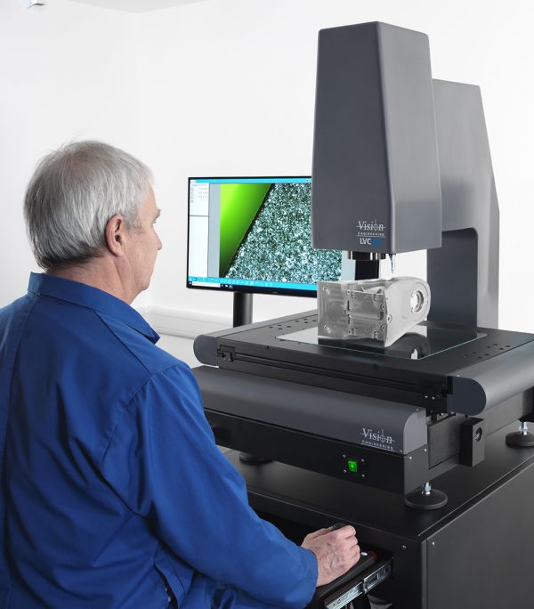 Man in blur overall measuring features on metal part with LVC 3-axis CNC measurement system