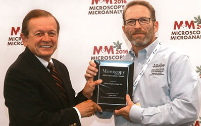 Vision Engineering employee being presented with Microscopy Today Innovation Award