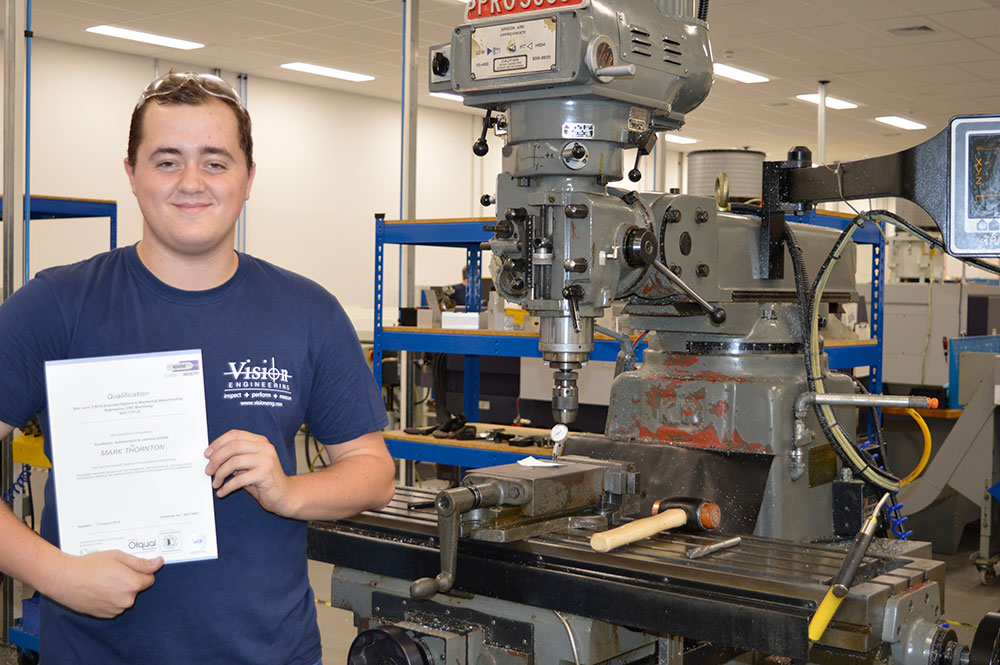 Mark Thornton holding his certificate in Vision Engineering CNC machine shop