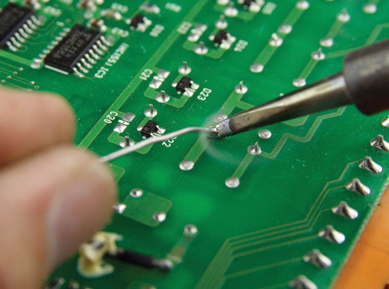 hands soldering component to PCB