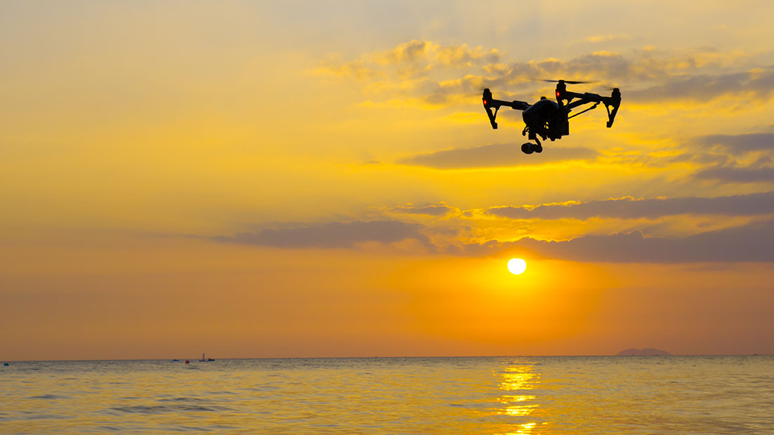 Drone flying over the sea at sunset