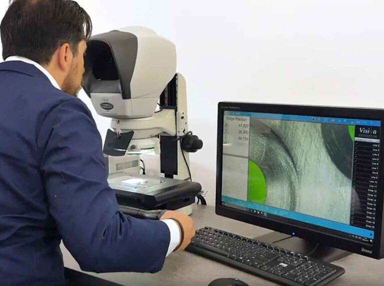 man in blue overall using Swift PRO Duo toolmakers microscope to measure metal part