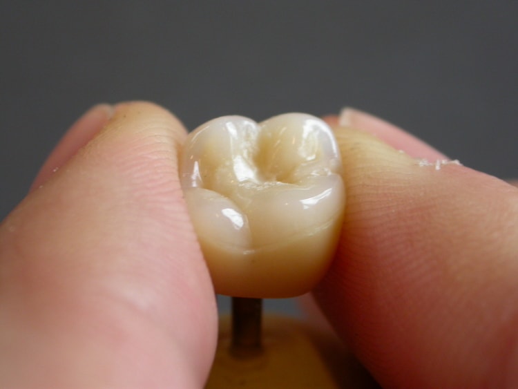 Dental crown tool held between fingers