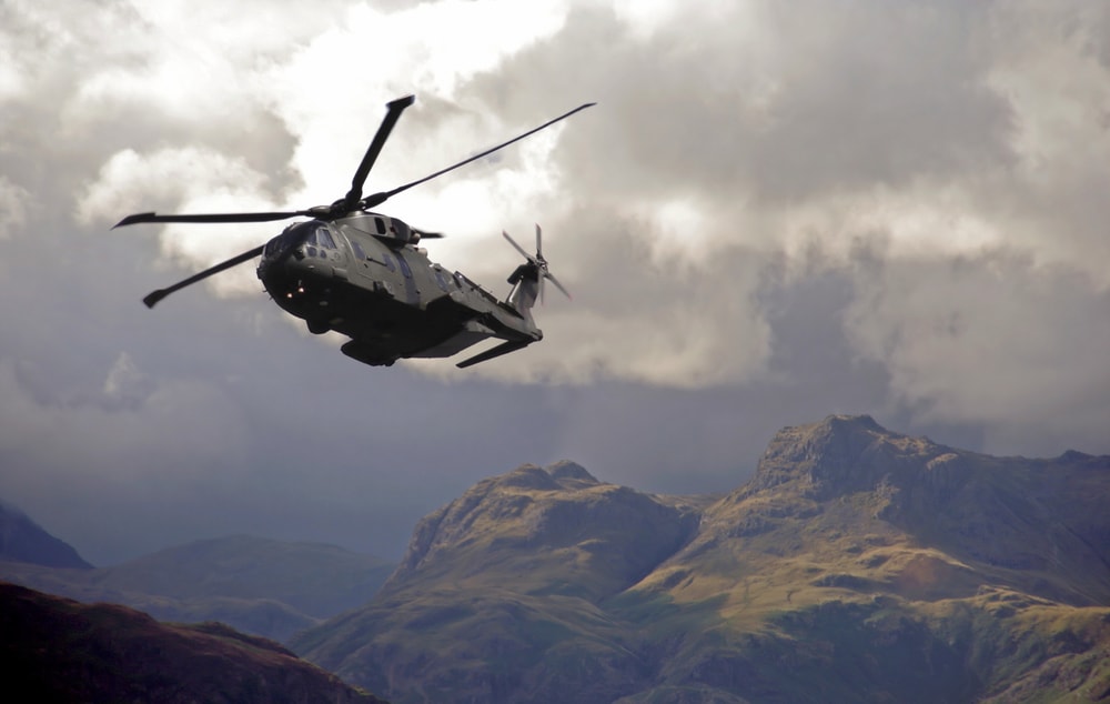 helicopter flying in sky with mountains in background