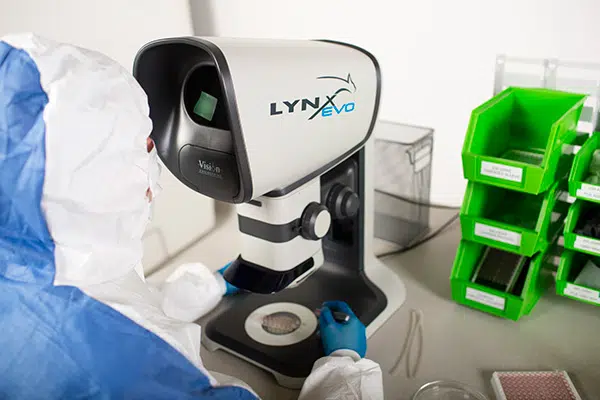 Person wearing a hazmat suit in a laboratory using the Lynx EVO stereo microscope