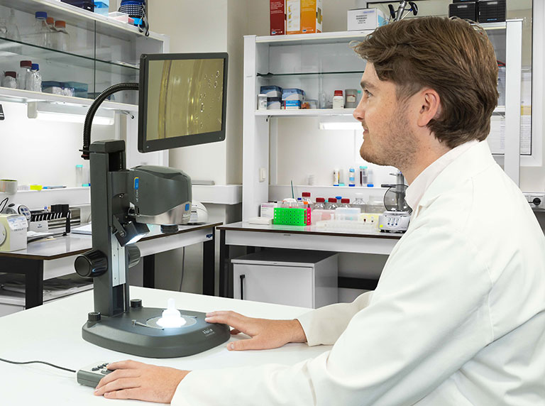 man in white coat using VE Cam digital microscope in a laboratory